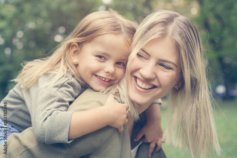  Little girl lying on mother's piggyback .