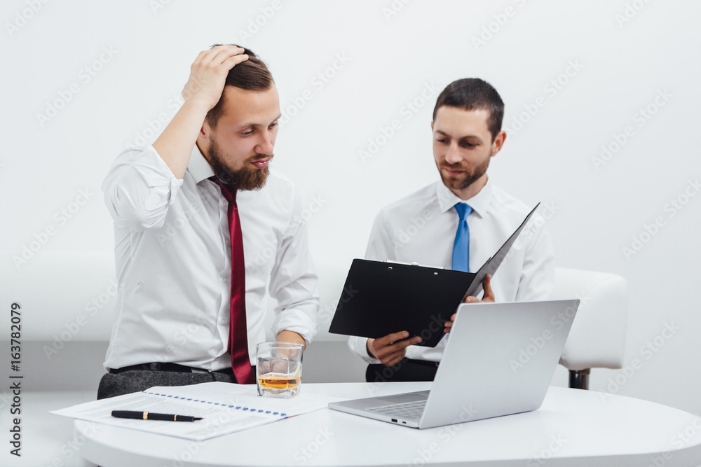 Two business partners working with documents, laptop and phone at office Two business partners working with documents, laptop and phone at office