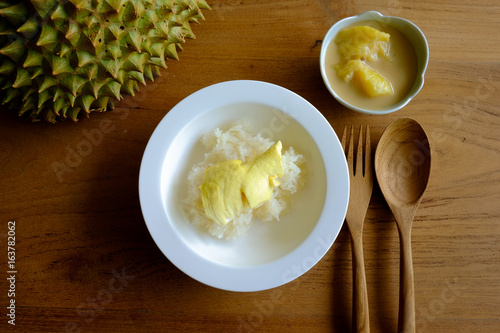 Sticky rice with durian and coconut milk separate ready to eat, set on the wooden table with wooden spoon