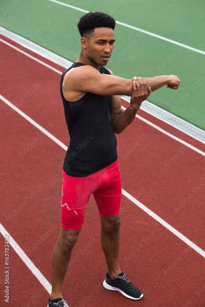 Concentrated african athlete man make stretching exercises