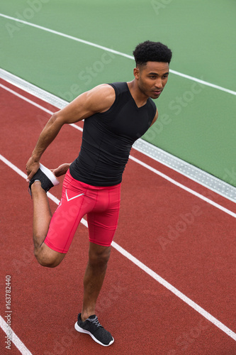 Concentrated african athlete man make stretching exercises © Drobot Dean