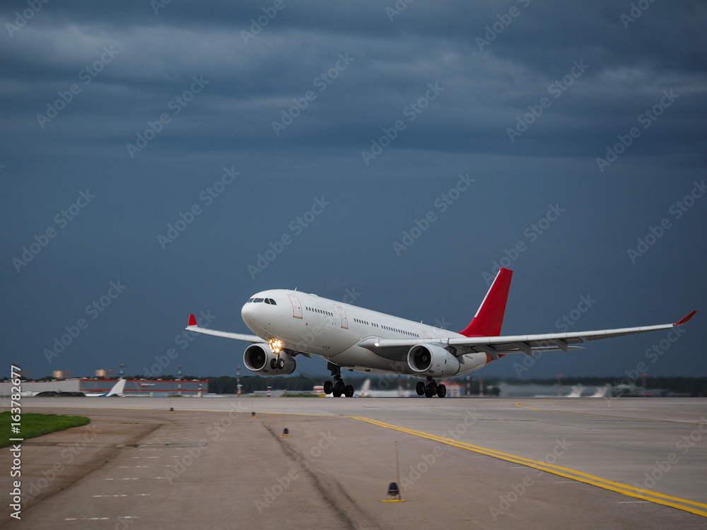 Airplane on the runway in the background of a rainy sky