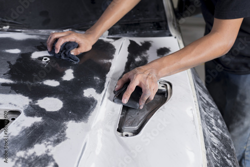 Auto body repair series: Closeup of mechanic wet-sanding car bonnet