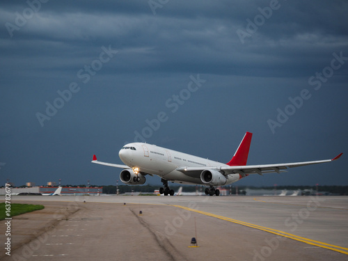 Airplane on the runway in the background of a rainy sky