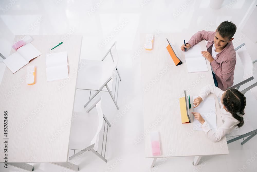 Fototapeta premium Overhead view of clasmated using digital tablets while sitting at desk in class