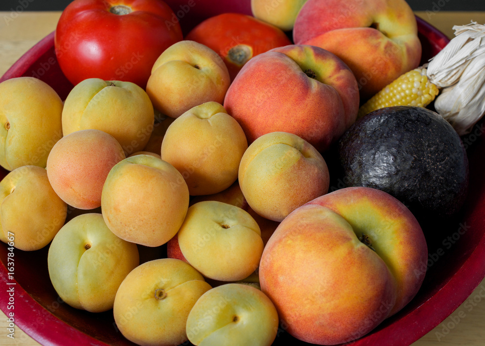 Closeup on fruits harvested in California at the end of summer, in red basket,  decorated with indian corn