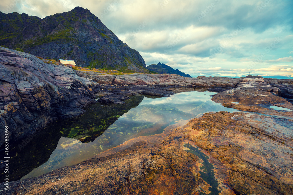 Rocky seashore with cloudy sky. Wilderness. Beautiful nature Norway. Lofoten islands. Reine