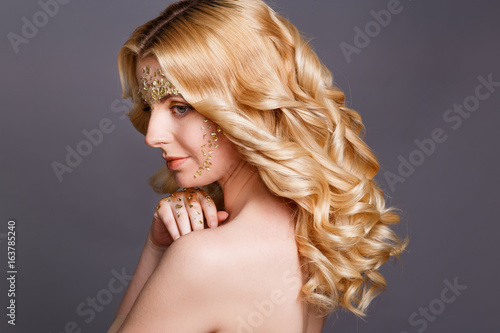 Beauty Woman Portrait. Beautiful fashion model with professional Makeup and Manicure with golden foil glitter. Gold colors. 