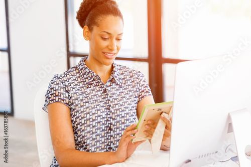 Portrait of smiling afro-american office worker in offfice holding a photo frame photo