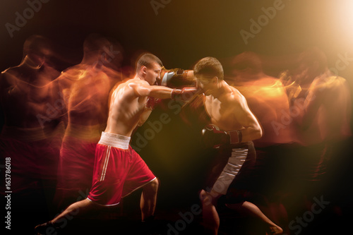 The two male boxers boxing in a dark studio