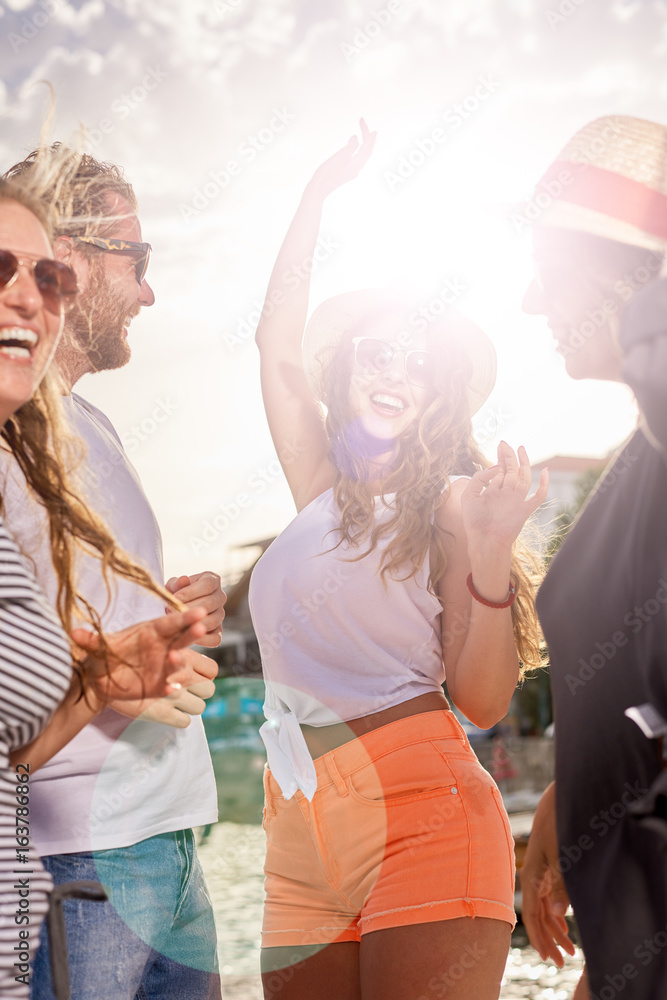 Group of people dancing, chatting and having a good time at beach party - obrazy, fototapety, plakaty 