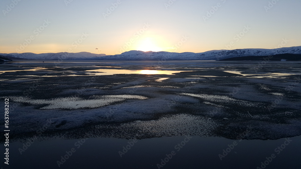 Midnight sun over an icy lake in Abisko