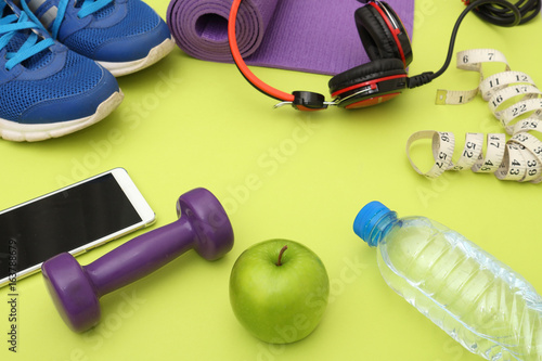 Athlete's set dumbbells and bottle of water, Yoga mat, sport shoes, on yellow background. Concept healthy lifestyle, sport and diet. Sport equipment. Copy space