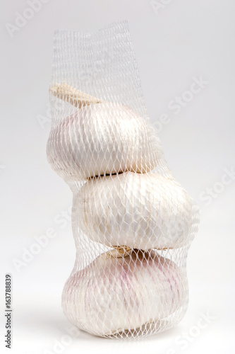 Row white garlic bulbs in net package with white background, general and useful seasoning for tasty foods.