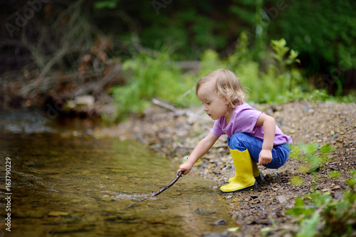 The little cute girl walks at the river in the fresh air