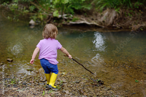 Fototapeta Naklejka Na Ścianę i Meble -  The little cute girl walks at the river in the fresh air
