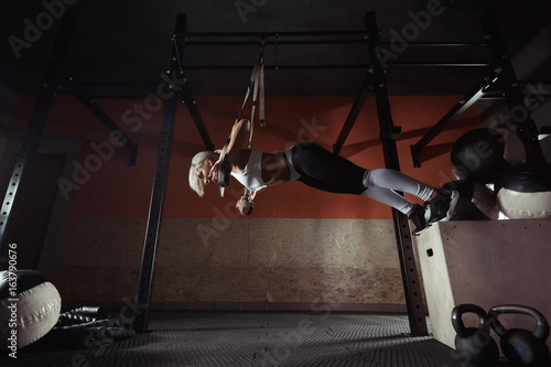 Fitness woman workout on the TRX in the gym