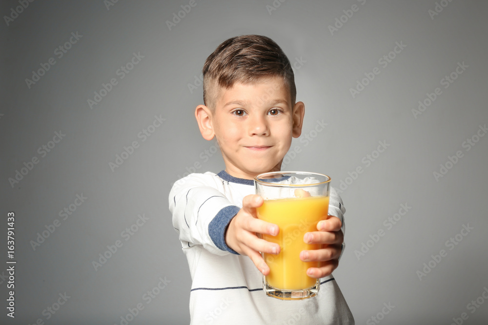 Cute little boy with glass of juice on grey background Cute little boy with glass of juice on grey background