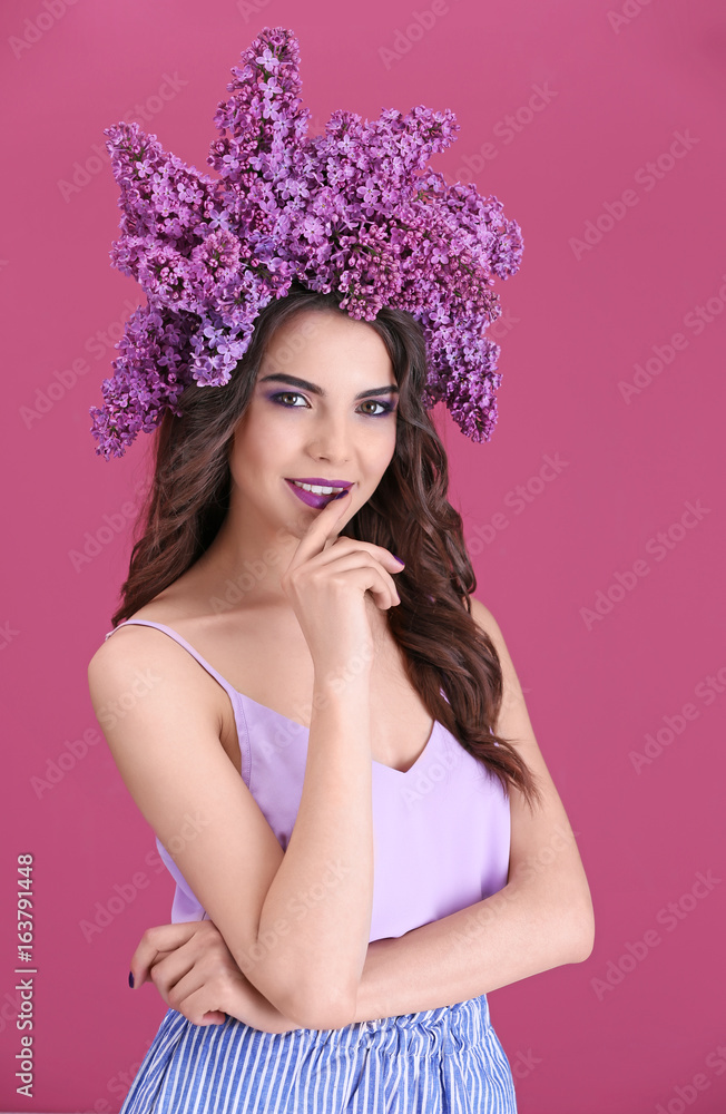 Beautiful young woman in wreath of lilac on color background Beautiful young woman in wreath of lilac on color background