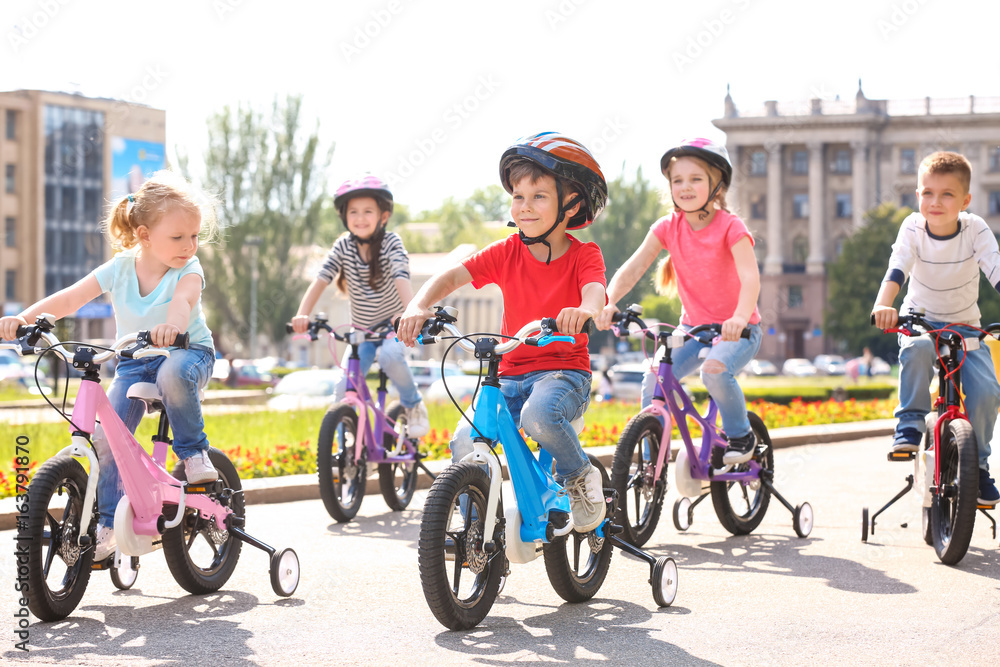 Fototapeta premium Cute little children riding bicycles outdoors on sunny day