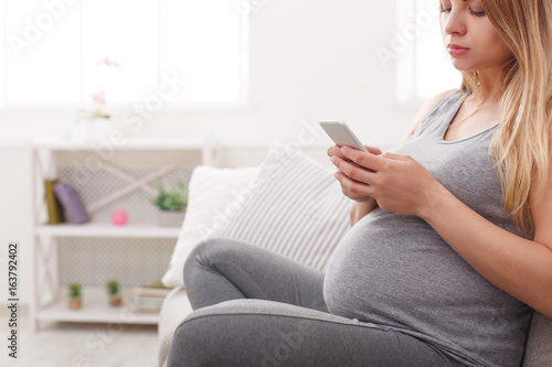 Young pregnant woman using smartphone copy space