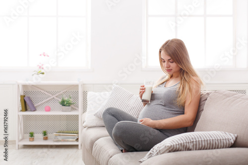 Pregnant woman drinking glass of milk copy space