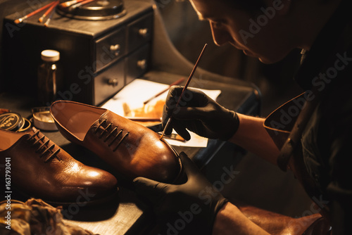 Cropped image of young concentrated man shoemaker