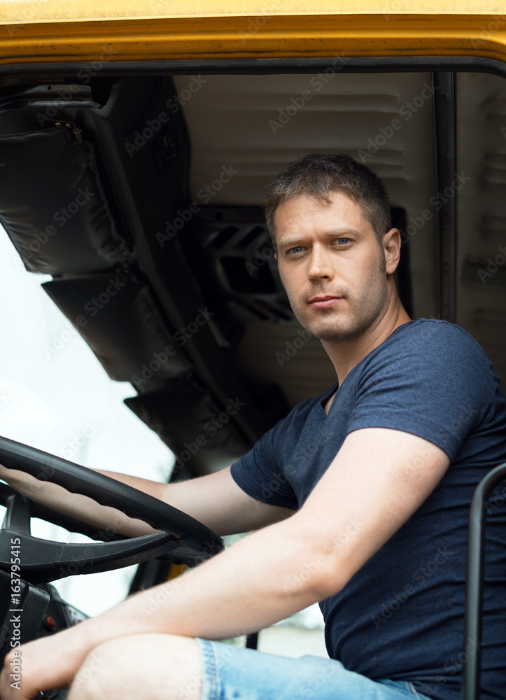 Obraz premium Male trucker in cabin of his yellow truck.