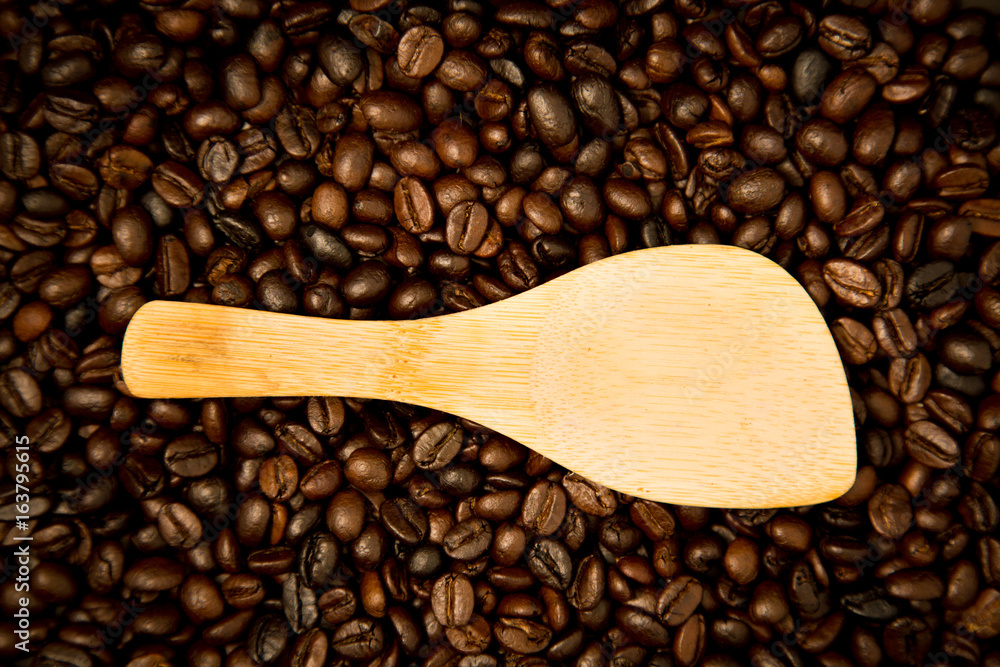 Fototapeta premium Wood spoon rests on coffee beans.