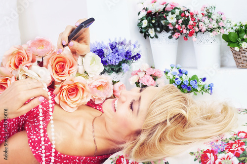 Fototapeta Naklejka Na Ścianę i Meble -  Happy woman with flowers texting message on phone