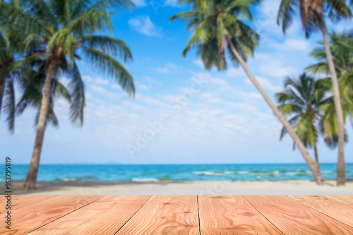 Wooden table in front of abstract blurred sea   coconut tree background. For present your products. Summer Concept