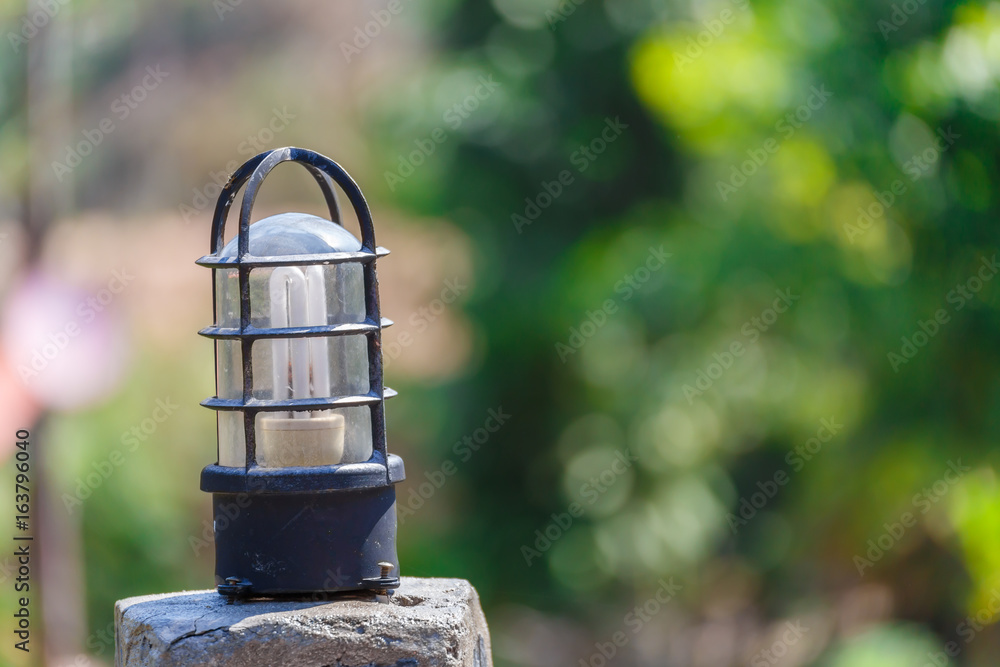 Light bulb on concrete pole with green bokeh background. Light bulb on concrete pole with green bokeh background.