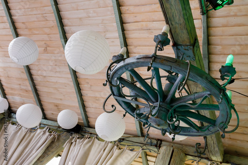 White balls and a wooden wheel with candle-lamps hang on the ceiling.