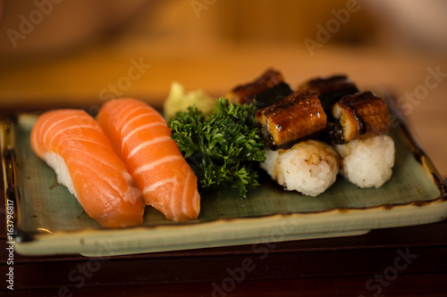 Sushi Salmon and Sushi eel is placed in a dish on a wooden table.