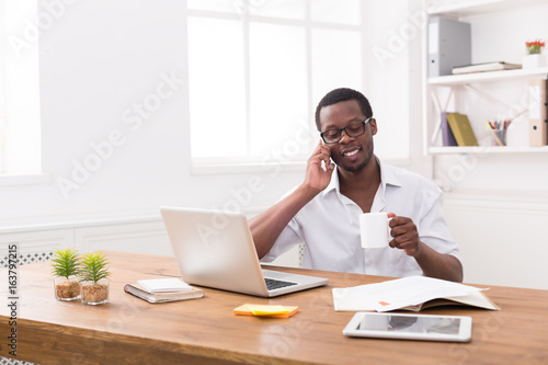 Young black businessman call mobile phone in modern white office