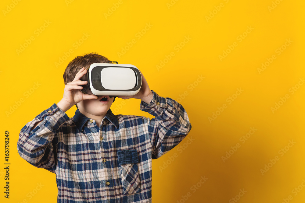 The boy wearing virtual reality goggles over yellow background. The boy wearing virtual reality goggles over yellow background.