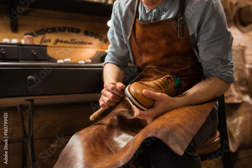 Bootmaker in workshop making shoes. photo