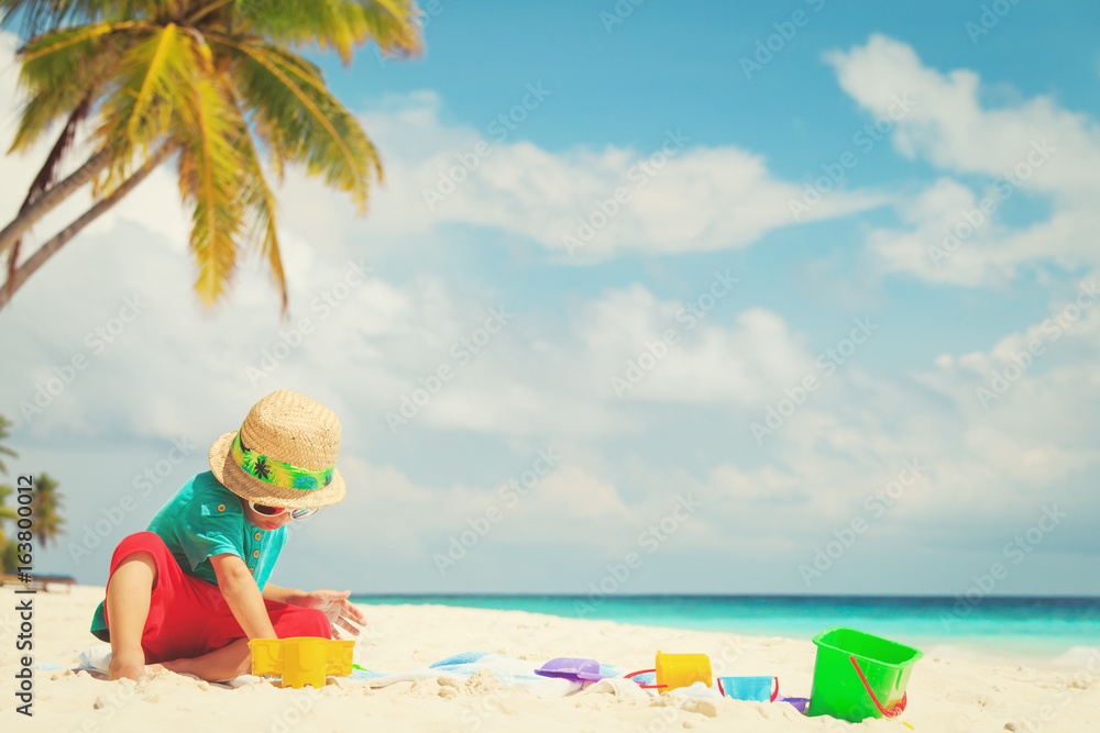 little boy play with sand and toys on beach