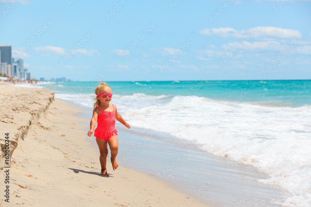 happy cute little girl running on beach
