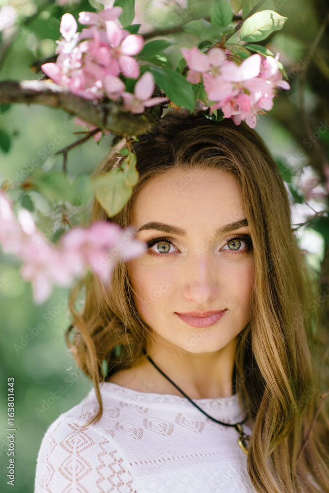 Young beautiful girl walking in a beautiful park among the flowering trees Young beautiful girl walking in a beautiful park among the flowering trees