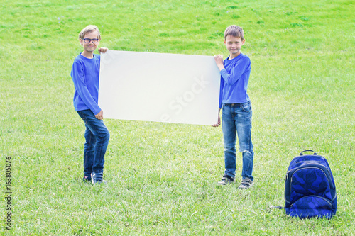 Children with blank white placard board outdoors