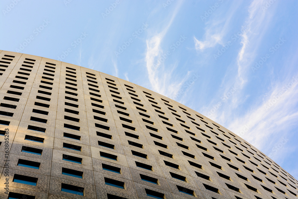 Low angle view of the concrete facade of an office building with blue sky.