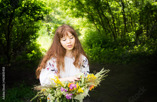 Pretty young woman in traditional dress with a wreath of wild flowers.