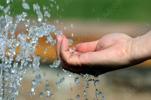 A man's hand over a small fountain .
