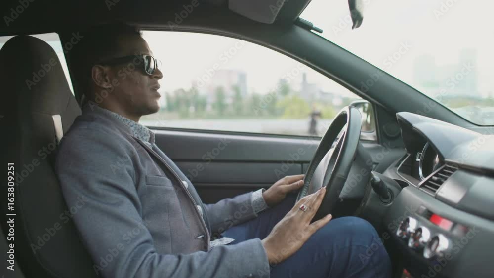 Upset and angry mixed race businessman sitting inside his car outdoors Upset and angry mixed race businessman sitting inside his car outdoors
