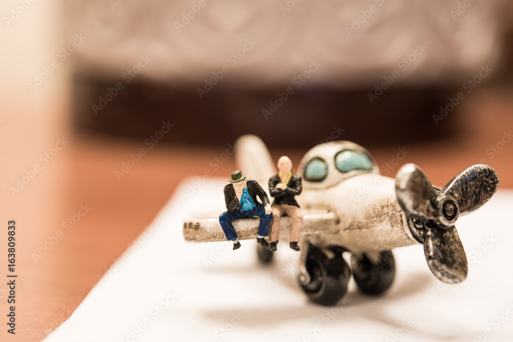 miniature people: businessman sitting on the wing of the plane. using as business travel concept miniature people: businessman sitting on the wing of the plane. using as business travel concept
