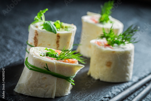 Closeup of rolls with vegetables and cheese on black rock