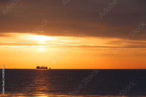 Dawn at the sea. In the distance a ship can be seen.