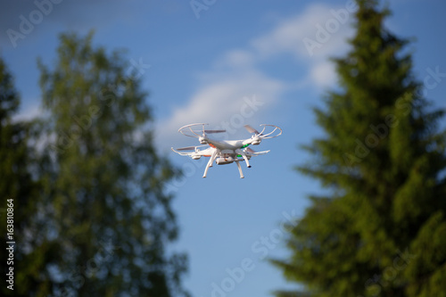 Drone with the camera against the blue sky.