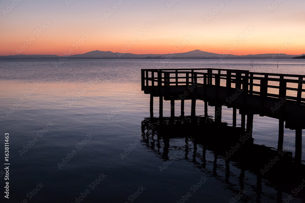 A pier on a lake at dusk, with beautiful soft and warm colors